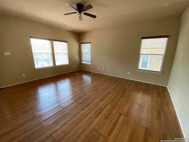 a view of an empty room with wooden floor and a window