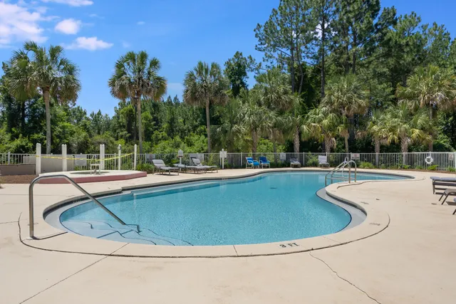 a view of swimming pool that has lawn chairs with plants