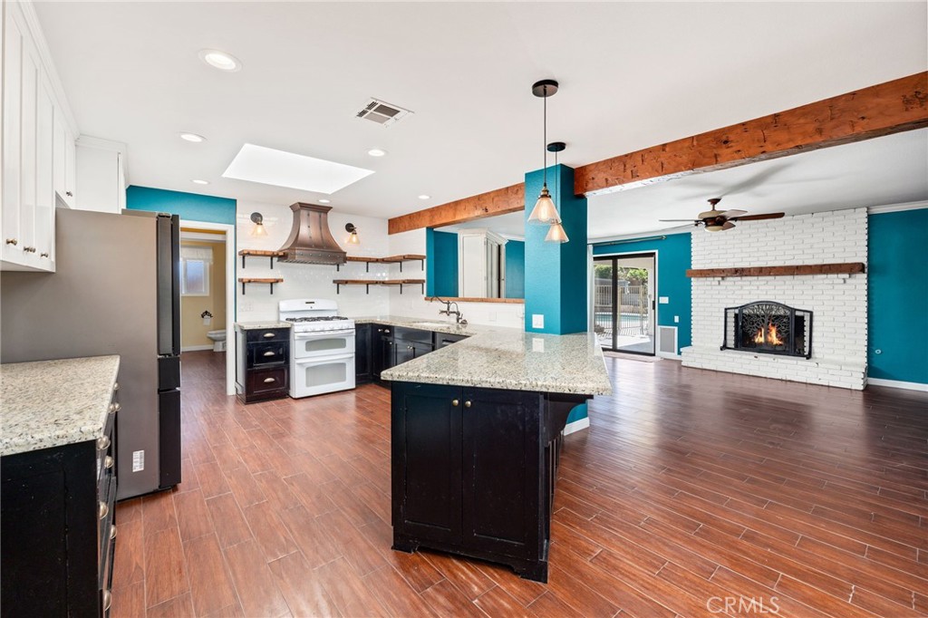 26655 Del Rosa Drive Hemet, CA 92544 - Photo 16 of 57 a kitchen with stainless steel appliances granite countertop a refrigerator a sink dishwasher a stove and a dining table with wooden floor