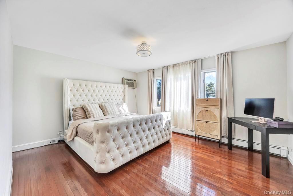 179 Sterling Road Elmont, NY 11003 - Photo 11 of 20 Bedroom with wood-type flooring, an AC wall unit, and a baseboard radiator