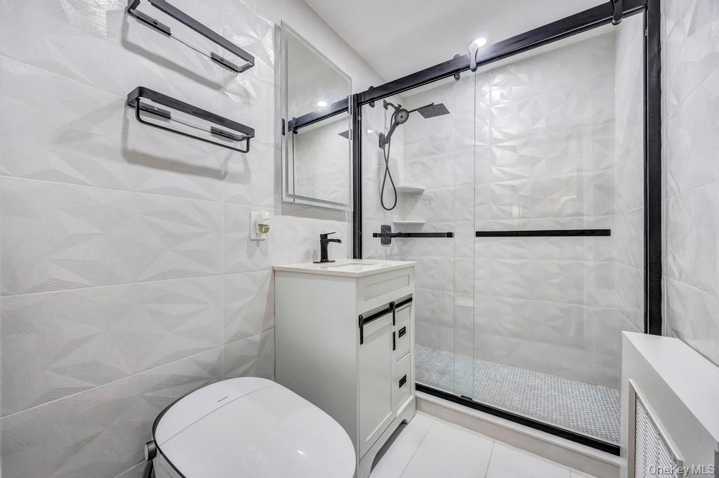 179 Sterling Road Elmont, NY 11003 - Photo 12 of 20 Bathroom with tile walls, a stall shower, vanity, and light tile patterned floors