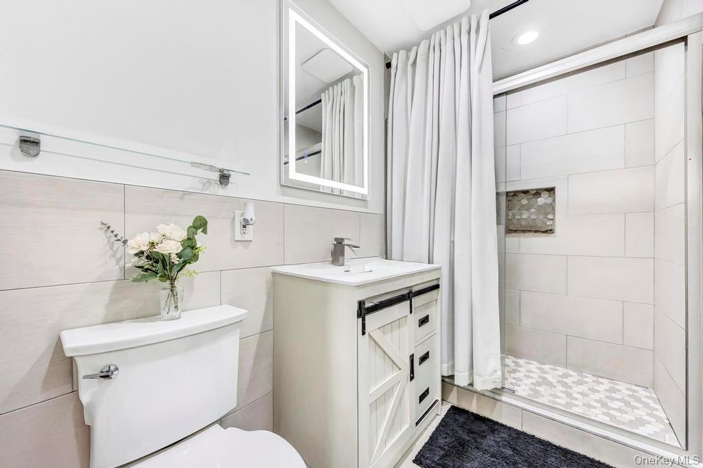 179 Sterling Road Elmont, NY 11003 - Photo 14 of 20 Full bathroom featuring a shower stall, vanity, tile walls, and tile patterned floors