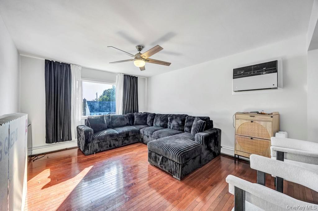 179 Sterling Road Elmont, NY 11003 - Photo 4 of 20 Living room featuring wood-type flooring, a wall unit AC, and ceiling fan