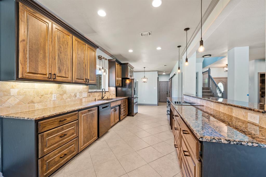 508 Chandler Road Keller, TX 76248 - Photo 9 of 39 Multiple pull out drawers for pots and pans. Granite counters. Under cabinet lighting. Breakfast bar. Tumbled stone backsplash. The large French door refrigerator conveys with the property. Modern hardware. Flat surface cooktop with downdraft.