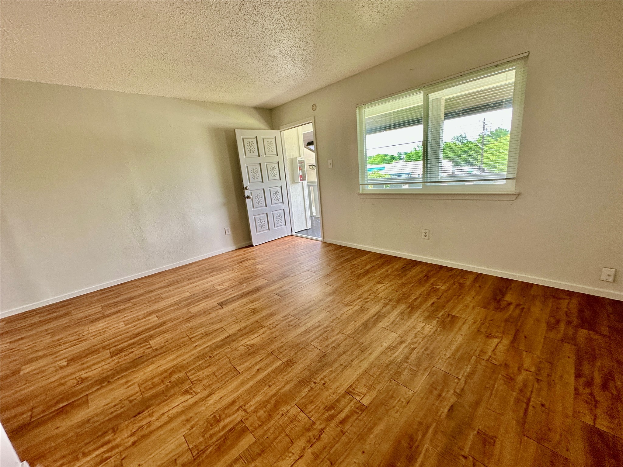 10810 Newmont Road, Unit 7 Austin, TX 78758 - Photo 2 of 13 Open living space featuring wood-look flooring and a window with horizontal blinds