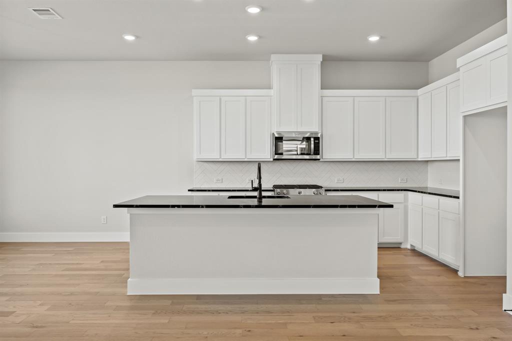 317 Chestnut Street Celina, TX 75009 - Photo 11 of 30 a kitchen with stainless steel appliances granite countertop a sink a stove a microwave a sink and white cabinets