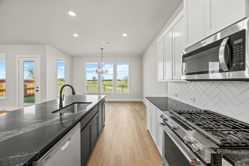 317 Chestnut Street Celina, TX 75009 - Photo 14 of 30 a kitchen with kitchen island granite countertop a sink stainless steel appliances and window