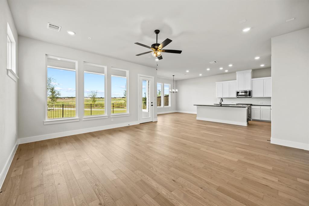317 Chestnut Street Celina, TX 75009 - Photo 7 of 30 wooden floor in an empty room with a kitchen