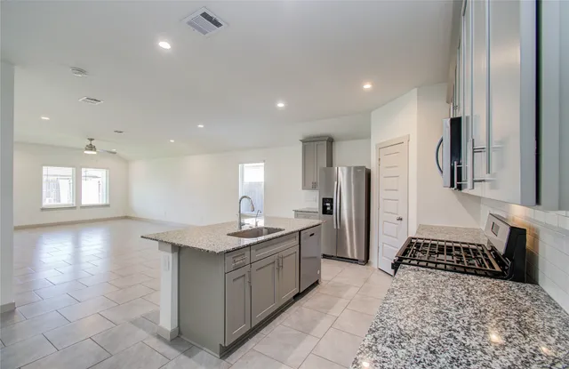 a kitchen with granite countertop a sink stove and cabinets