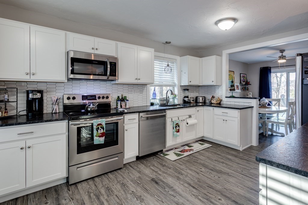 16 Vinton Road Holland, MA 01521 - Photo 14 of 32 a kitchen with stainless steel appliances white cabinets a sink a stove a microwave and wooden floors