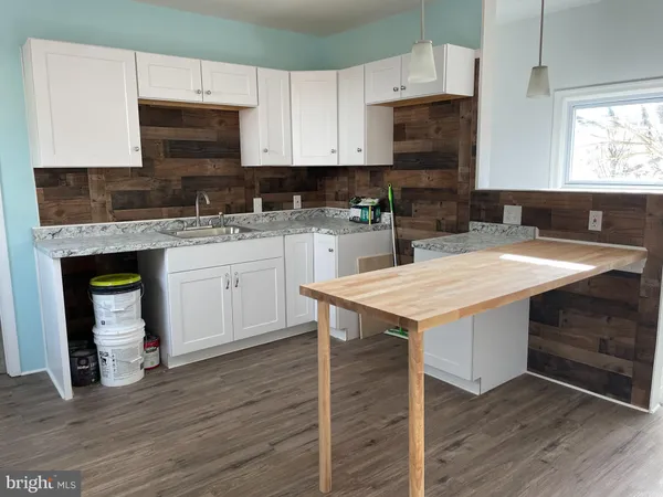 a kitchen with granite countertop wooden cabinets a stove top oven a sink and dishwasher with wooden floor