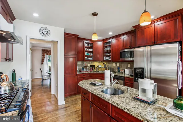 a kitchen with a refrigerator a stove a sink and a dining table with wooden floor