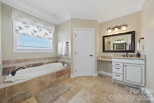 a spacious bathroom with a tub sink and mirror