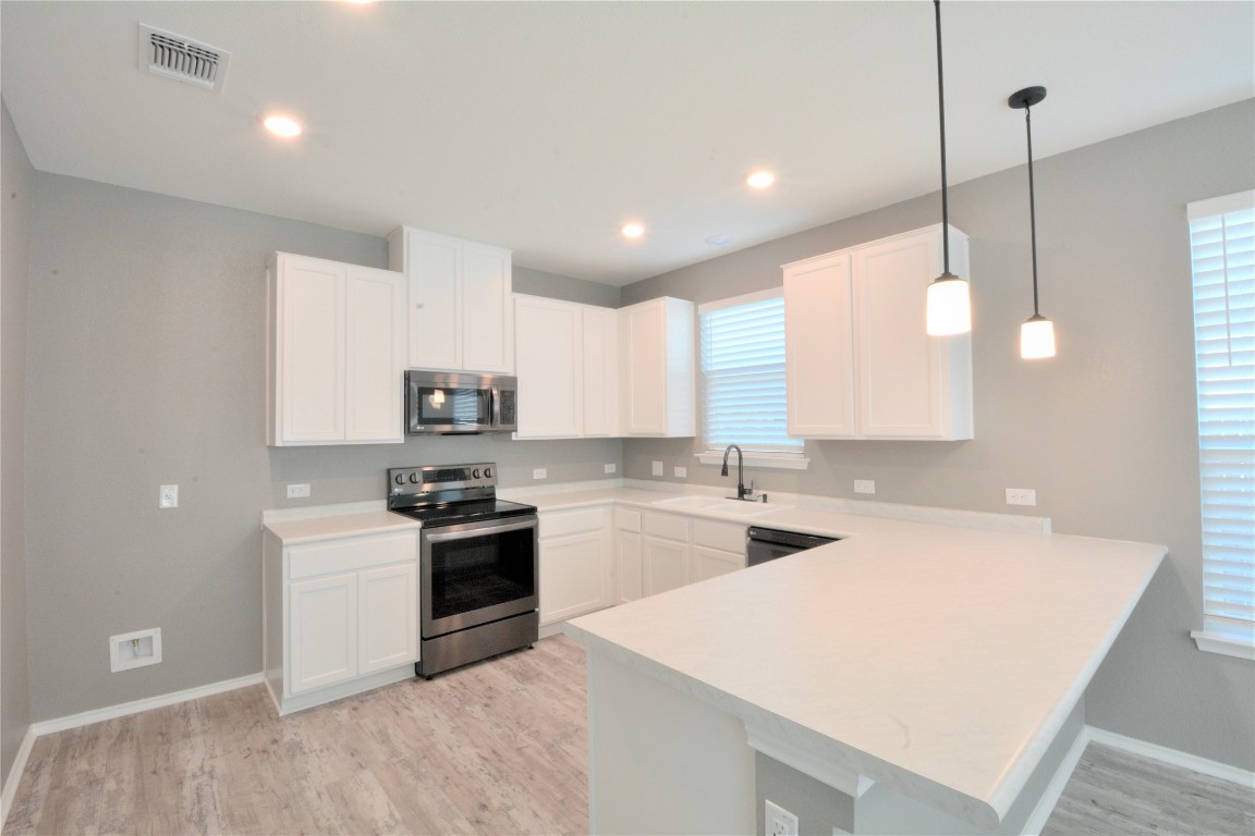 522 Thunder Valley Trail Georgetown, TX 78626 - Photo 6 of 24 a kitchen with stainless steel appliances granite countertop a sink a stove a refrigerator and white cabinets with wooden floor