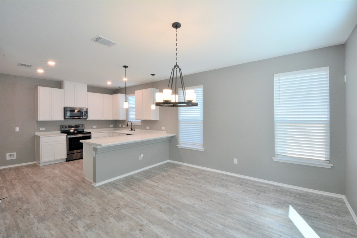 522 Thunder Valley Trail Georgetown, TX 78626 - Photo 8 of 24 a kitchen with kitchen island granite countertop a stove a sink a center island and a wooden floor
