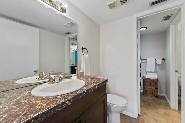 a bathroom with a granite countertop sink a toilet and a mirror