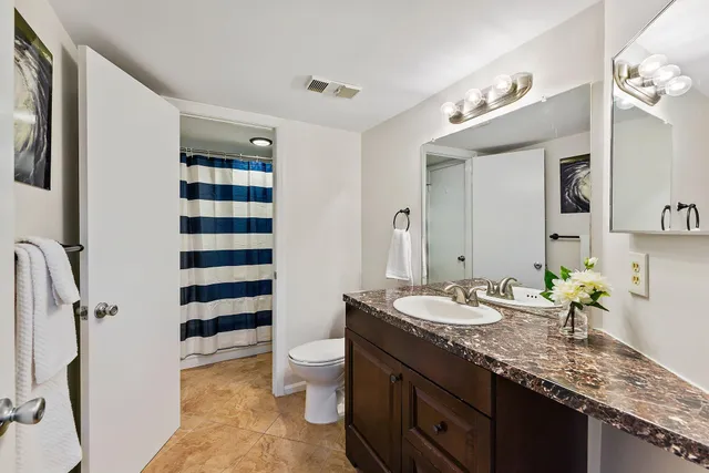 a bathroom with a granite countertop sink mirror vanity and toilet
