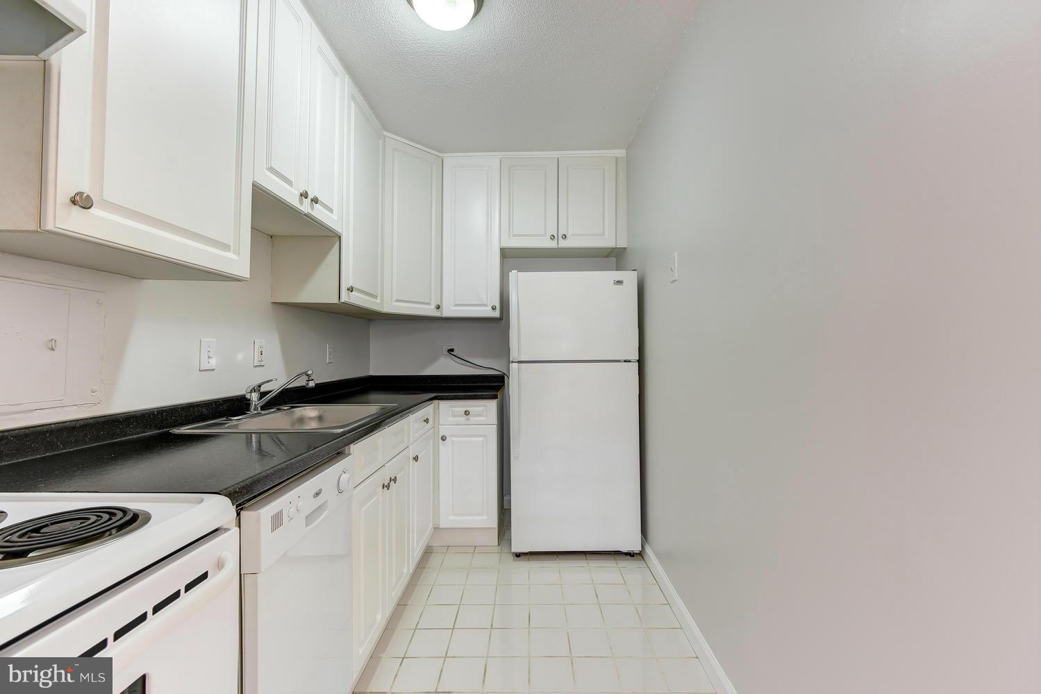 1311 Delaware Avenue Southwest, Unit S131 Washington, DC 20024 - Photo 11 of 18 a kitchen with granite countertop white cabinets and refrigerator