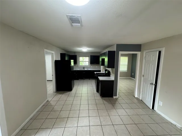 a view of kitchen with refrigerator cabinets and window