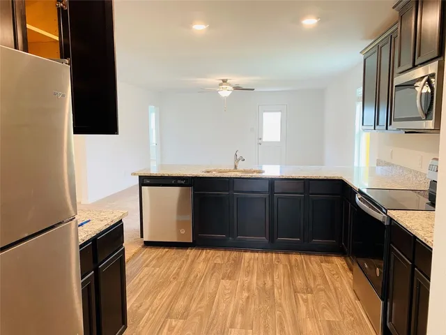 a kitchen with granite countertop a sink stainless steel appliances a counter space and cabinets