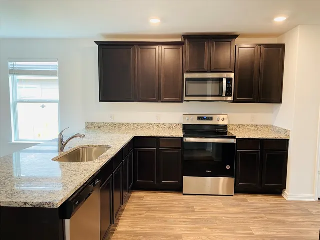 a kitchen with granite countertop wooden cabinets and stainless steel appliances