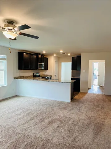 a view of an empty room with a kitchen and a window