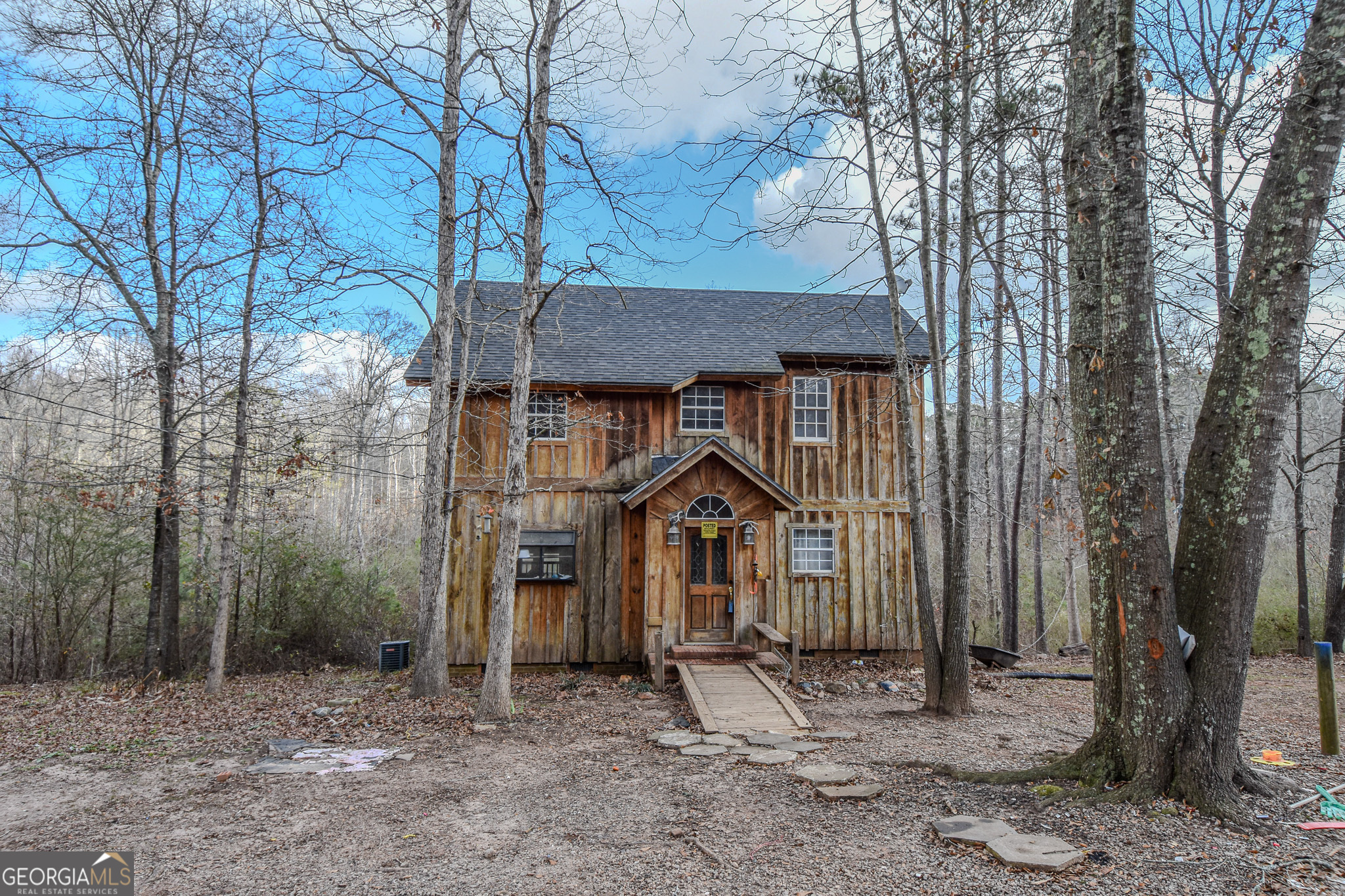 a wooden house with large trees and wooden fence