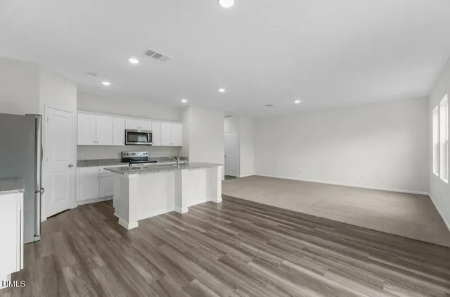 a kitchen with stainless steel appliances a refrigerator and white cabinets
