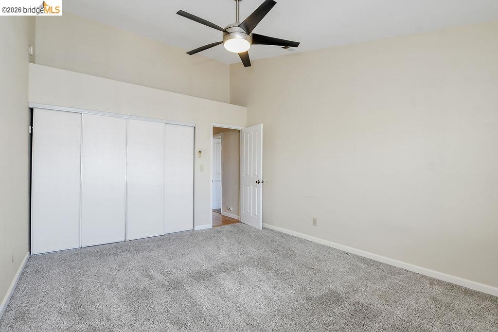 184 Pelican Loop Pittsburg, CA 94565 - Photo 35 of 56 Unfurnished bedroom featuring light colored carpet, a ceiling fan, a closet, and a high ceiling