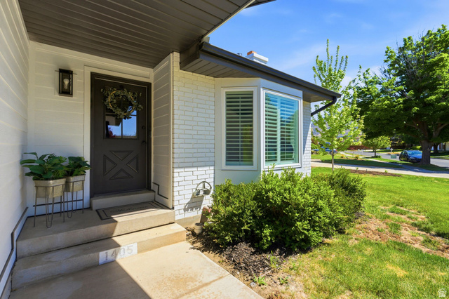 1405 Vintry Lane Murray, UT 84121 - Photo 4 of 44 Exterior showcasing white siding, painted brick accents, and a dark entry door with glass paneling