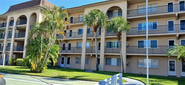 a front view of a residential apartment building with a yard and plants