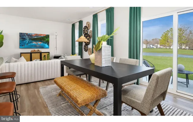 a view of a dining room with furniture one side kitchen view and wooden floor