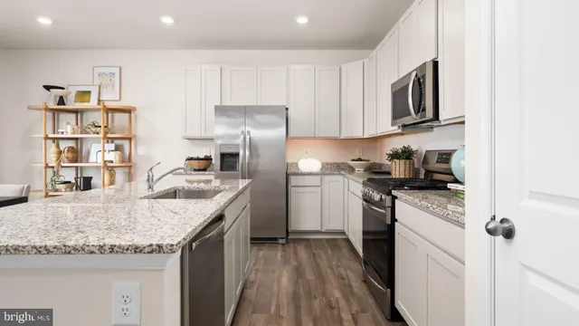 a kitchen with stainless steel appliances granite countertop a sink stove microwave and refrigerator
