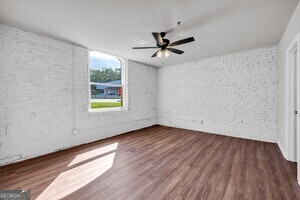 86 South Forest Avenue, Unit A Hartwell, GA 30643 - Photo 9 of 27 an empty room with wooden floor chandelier fan and windows