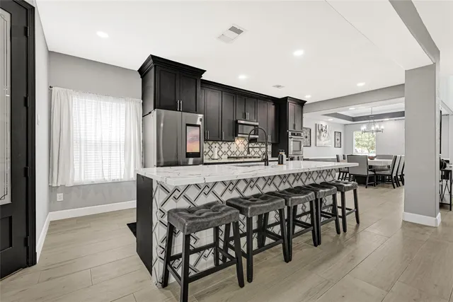 a kitchen with stainless steel appliances a table chairs refrigerator and microwave