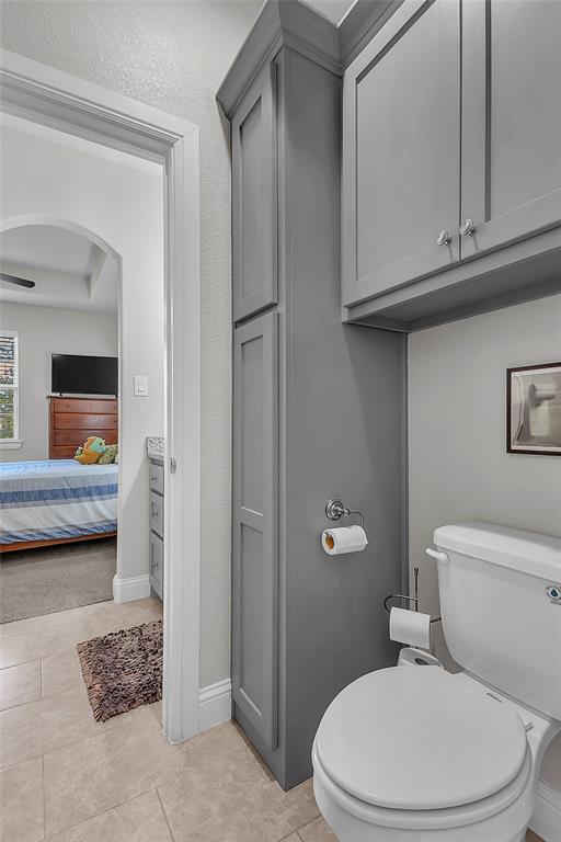 1014 Rennard Street Caddo Mills, TX 75135 - Photo 26 of 39 Bathroom featuring a built-in floor-to-ceiling cabinet, upper wall-mounted cabinetry, a toilet, and light-toned tile flooring