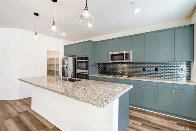 a kitchen with stainless steel appliances granite countertop a sink a oven and a refrigerator