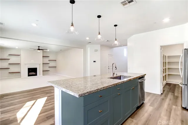 a large kitchen with kitchen island a stove a sink dishwasher a refrigerator and white cabinets with wooden floor