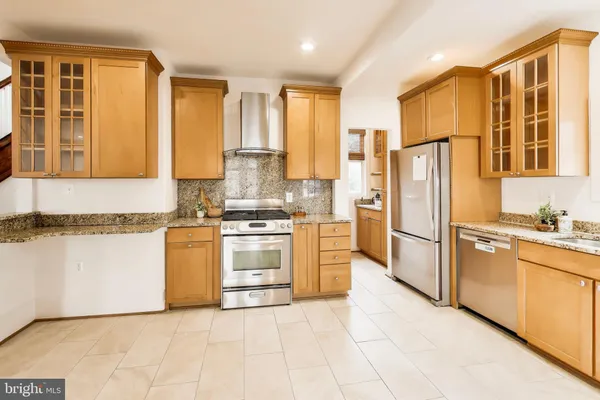 a kitchen with granite countertop a refrigerator a stove a sink and white cabinets with wooden floor