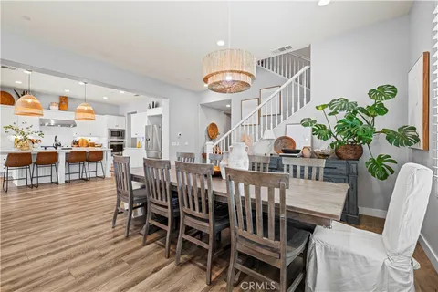 a kitchen with stainless steel appliances granite countertop a sink a stove a refrigerator and a dining table with wooden floor