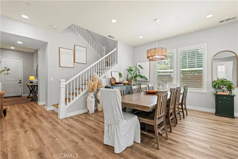 a kitchen with stainless steel appliances granite countertop a refrigerator a stove top oven a dining table and chairs with wooden floor