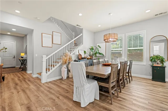 a kitchen with stainless steel appliances granite countertop a refrigerator a stove top oven a dining table and chairs with wooden floor