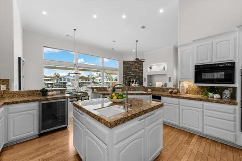 a kitchen with stainless steel appliances granite countertop a sink a stove and a wooden floors