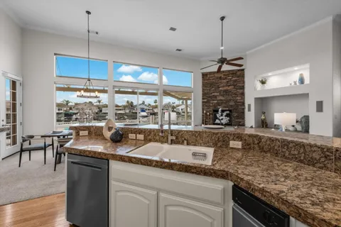 a kitchen with granite countertop a sink a counter top space and living room view