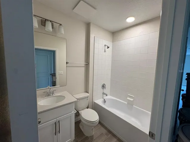 a bathroom with a granite countertop toilet a sink and a bathtub