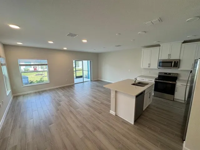a kitchen with granite countertop wooden floors a stove and a sink