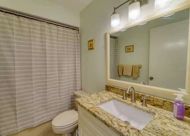 a bathroom with a granite countertop toilet sink and mirror