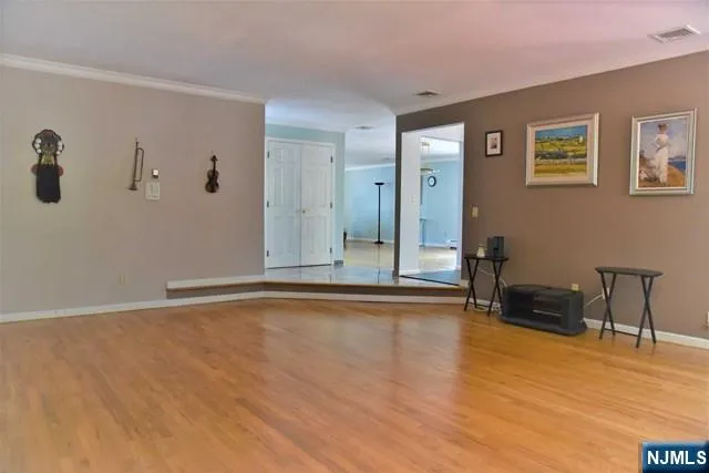 a view of an empty room with wooden floor and a chair
