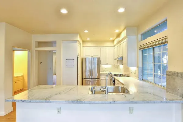 a kitchen with stainless steel appliances granite countertop a refrigerator a stove and white cabinets with wooden floor