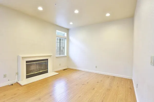 an empty room with wooden floor cabinet and windows